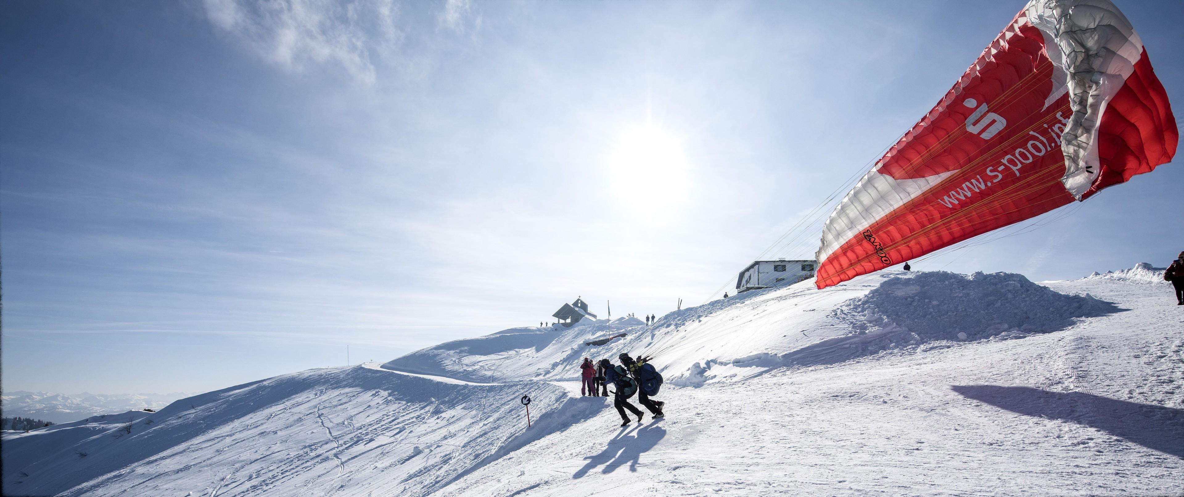 Ein Gleitschirm beim Start im Winter von einem schneebedeckten Berg