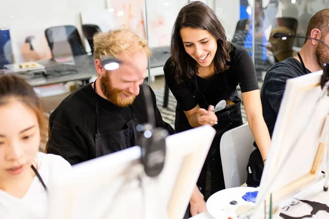 Mehrere Menschen sitzen vor Leinwänden und malen beim ArtNight Gruppenevent, angeleitet durch eine Künstlerin.