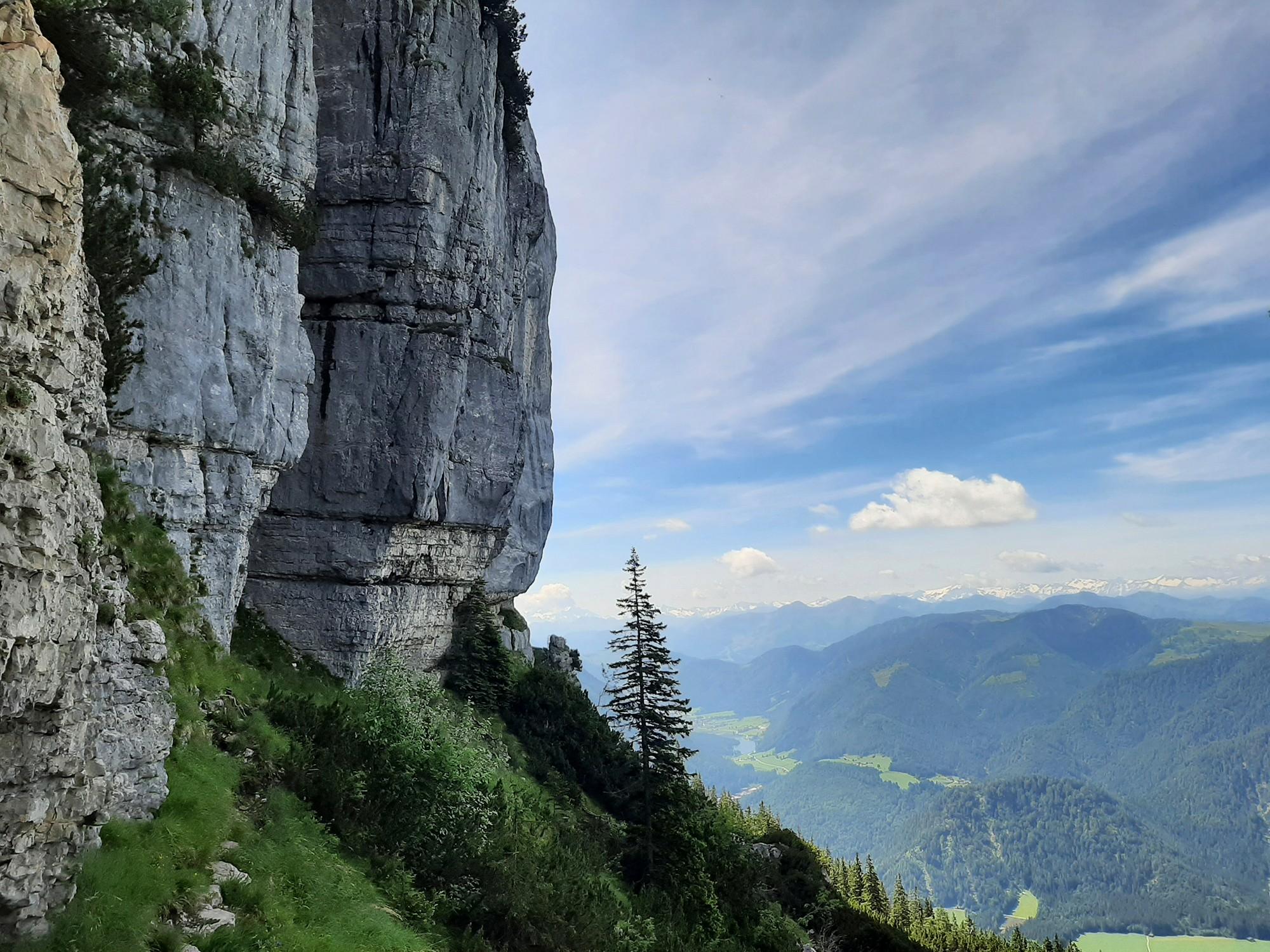 Steile Felsen in den Alpen mit bewaldetem Tal im Hintergrund