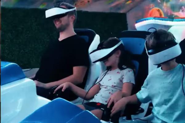 Ein Vater und seine zwei Kinder haben VR-Brillen auf und sitzen im Virtual-Reality-Kino.