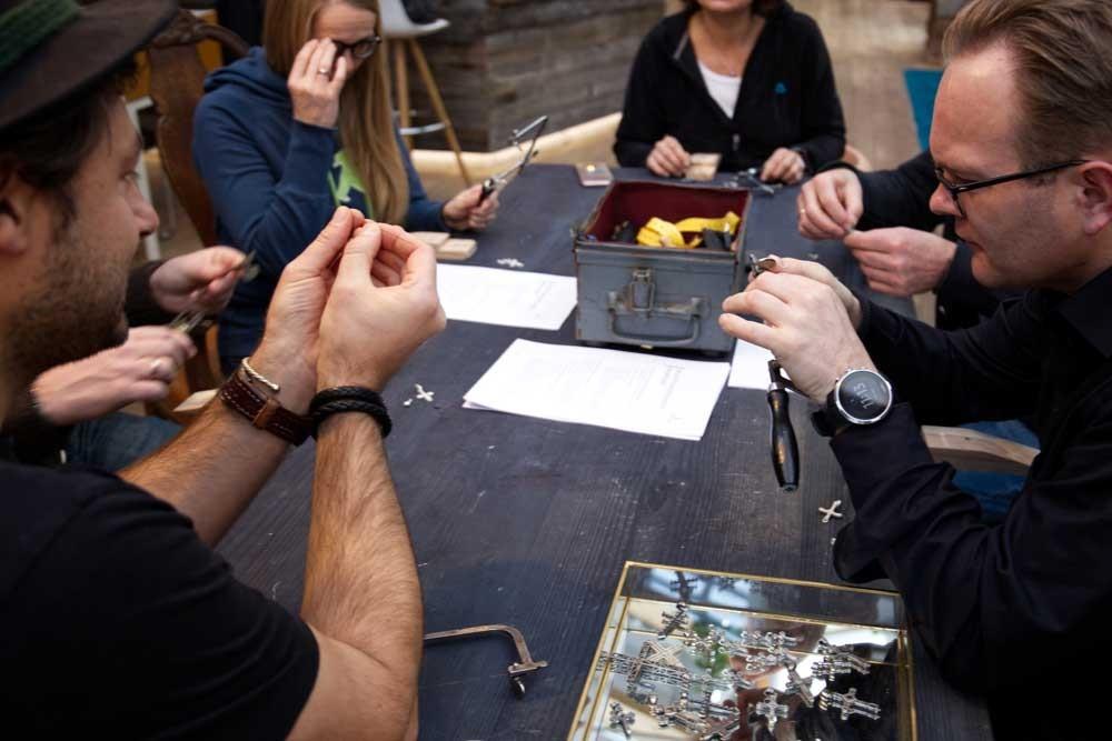 Teilnehmende stellen bei einem Schmuck-Workshop einen Gipfelkreuz-Anhänger her