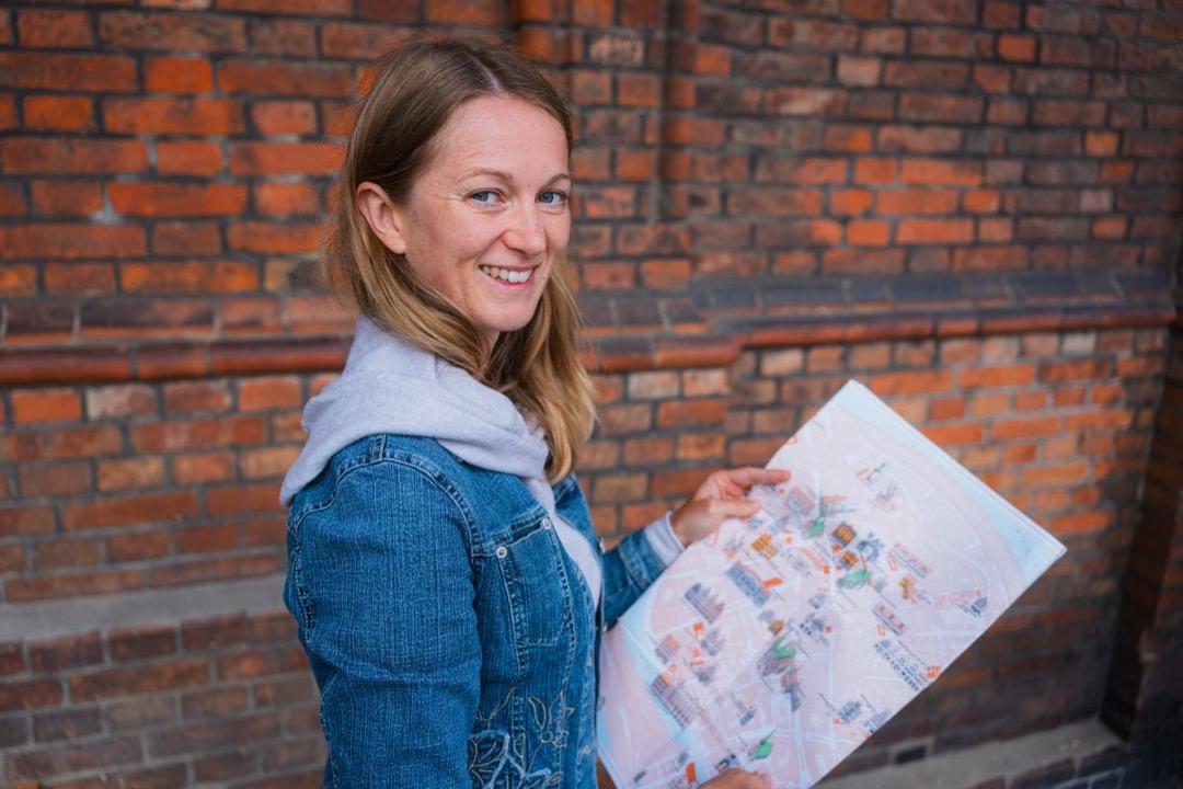 Frau mit Stadtplan vor Backsteinmauer bei Stadtführung in Lübeck.