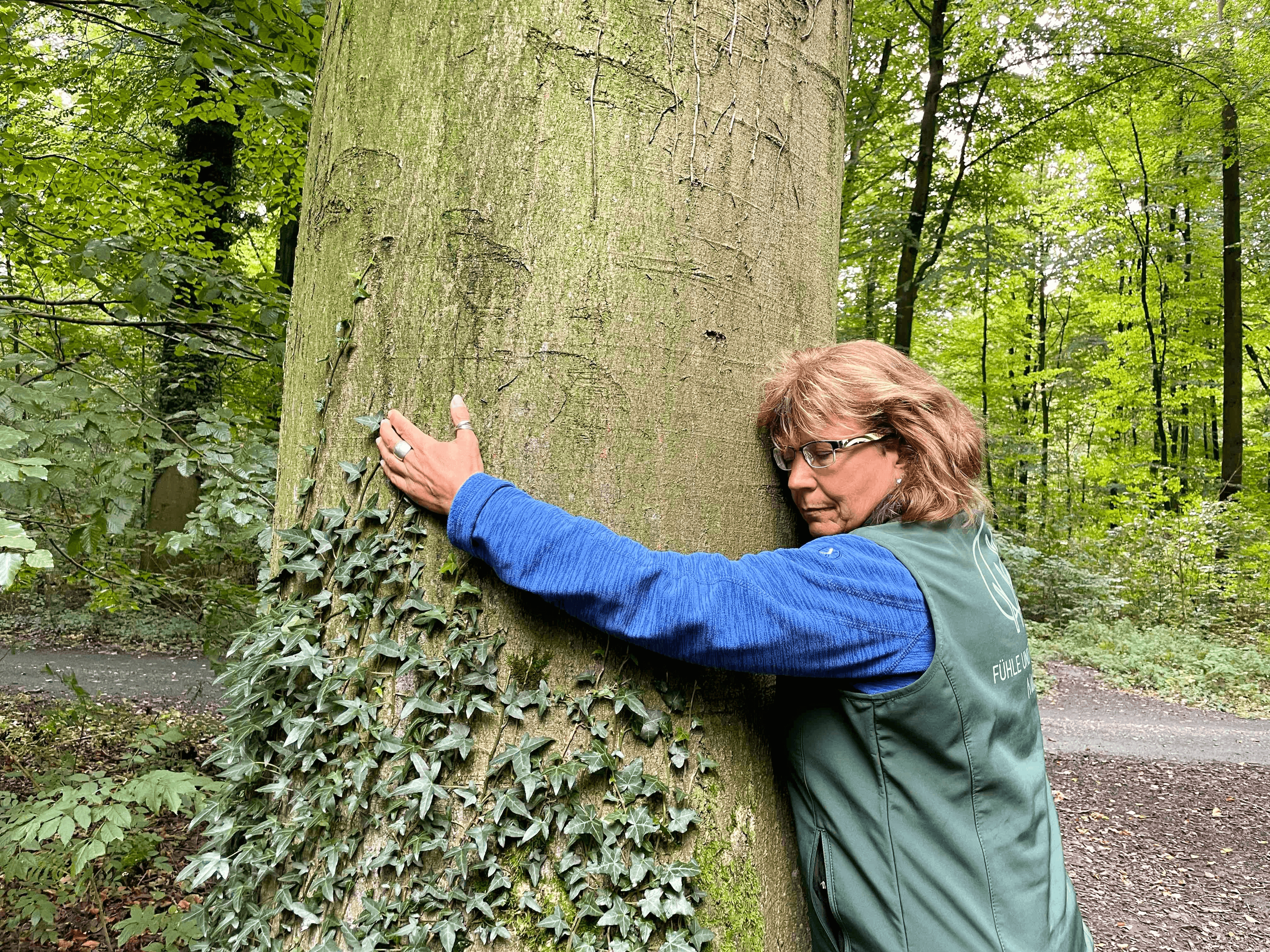 Eine Frau umarmt während eines Waldbaden-Retreats einen Baum