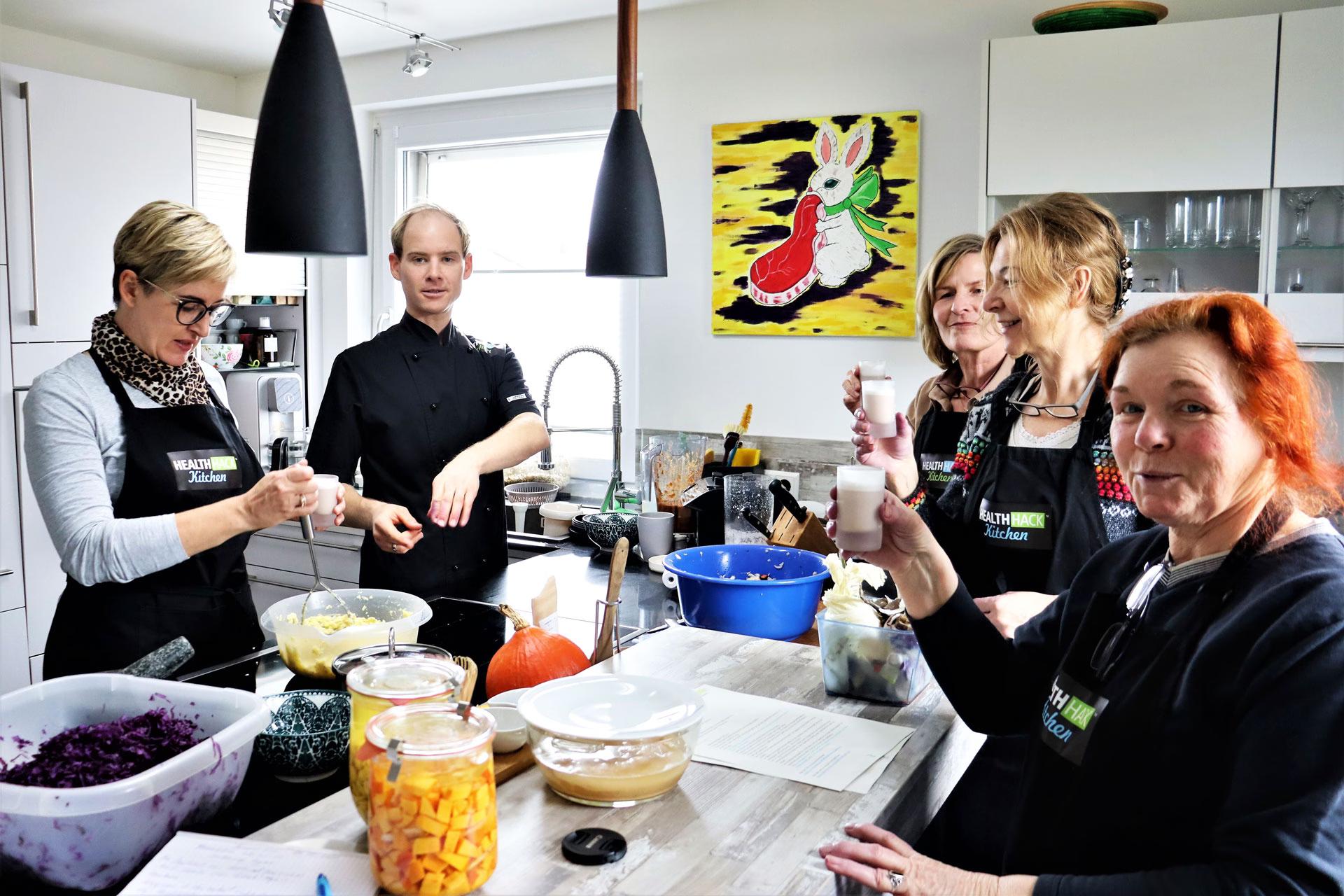 Vier Teilnehmerinnen des Kochkurses "Grundlagen der Fermentation" stehen in der Küche, daneben der Küchenchef.