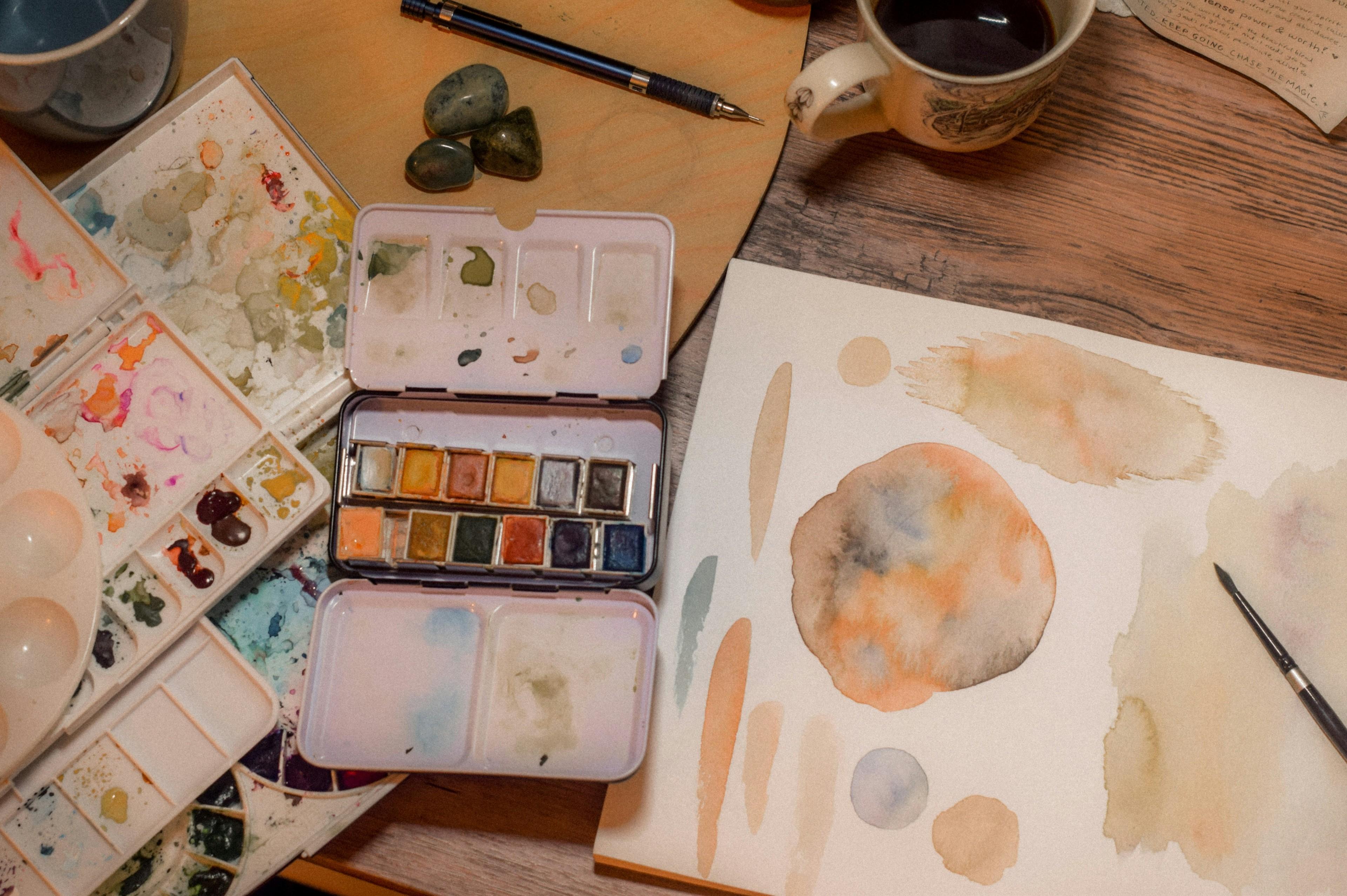 Aquarell-Farben und bemalte Blätter auf einem Tisch
