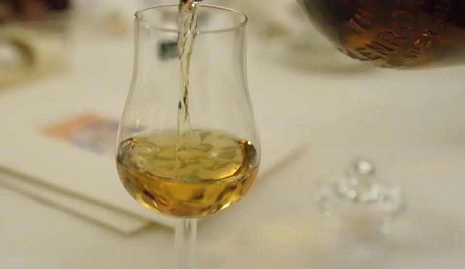 Ein heller Whisky wird bei einer Whisky-Probe in ein Glas eingeschenkt