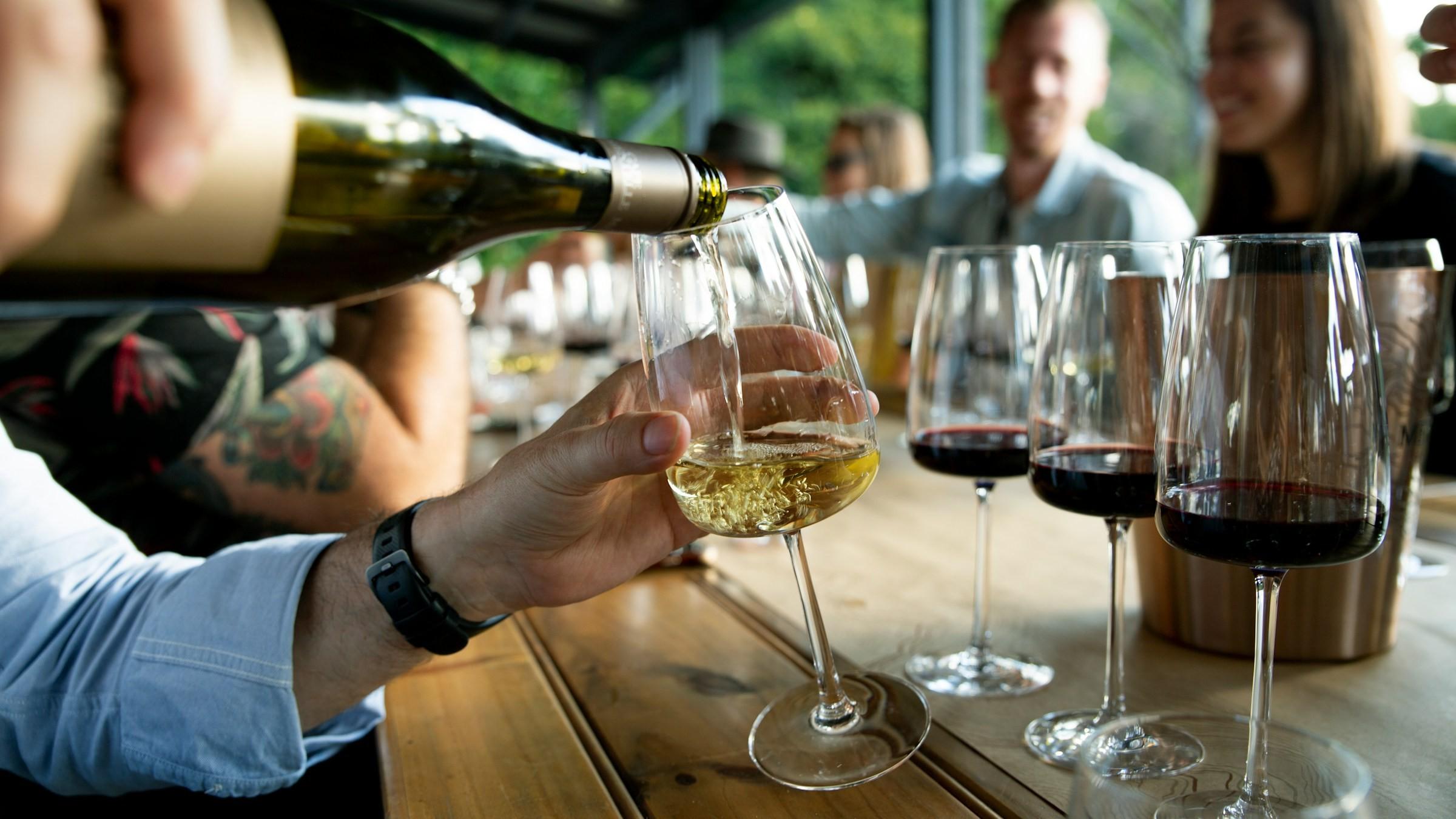 Ein Mann schenkt bei einem Weintasting Wein in ein Glas ein