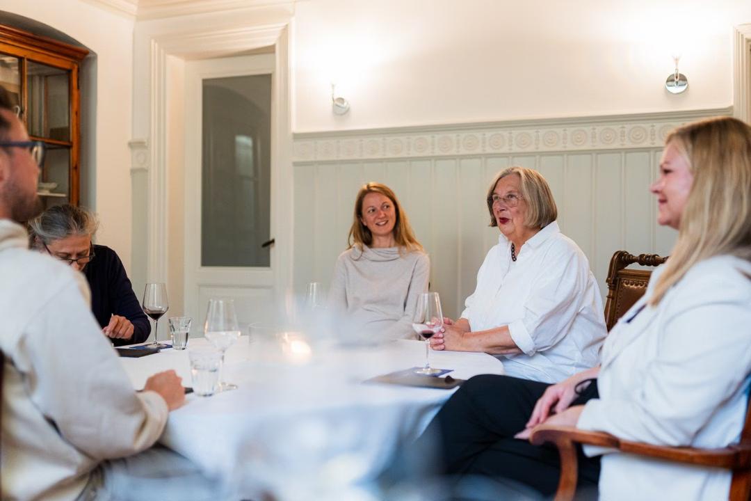 Menschen sitzen an einem Tisch in einem hellen, getäfelten Raum in Lübeck.