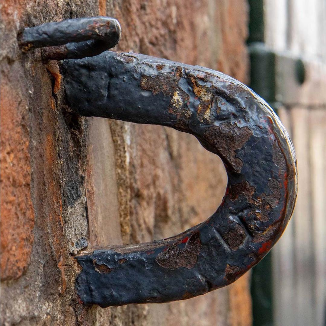 Nahaufnahme eines alten, rostigen Eisenhakens an einer Backsteinwand in Lübeck.