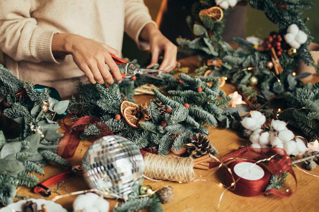 Eine Person dekoriert einen Adventskranz DIY-Workshop: Adventskranz binden in Lübeck.