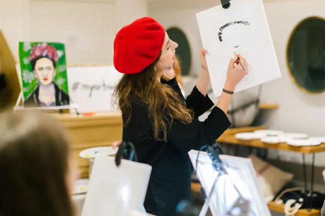 Eine Künstlerin mit roter Mütze gibt Maltipps an der ArtNight.