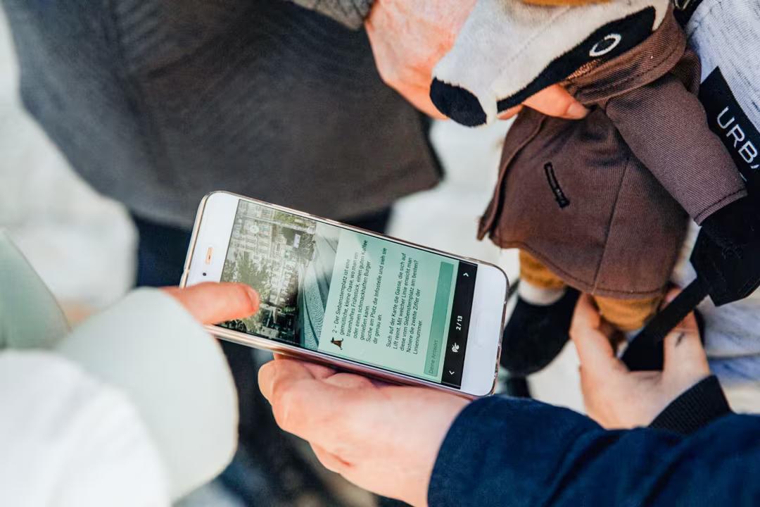 Nahaufnahme eines Smartphones mit Beschreibungen des Detektiv-Trail Grömitz.