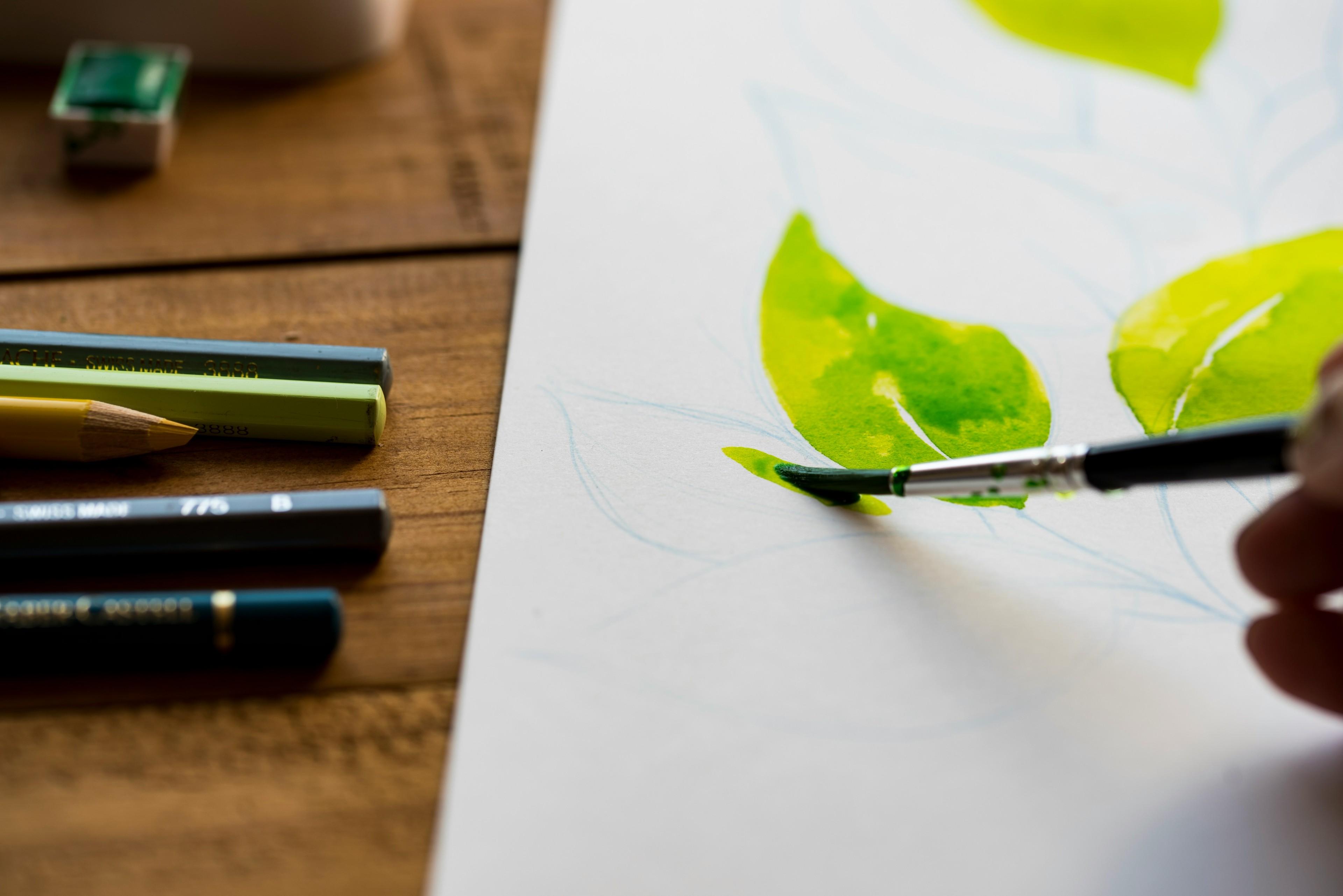Ein Pinsel auf einer Aquarellzeichnung von grünen Blättern
