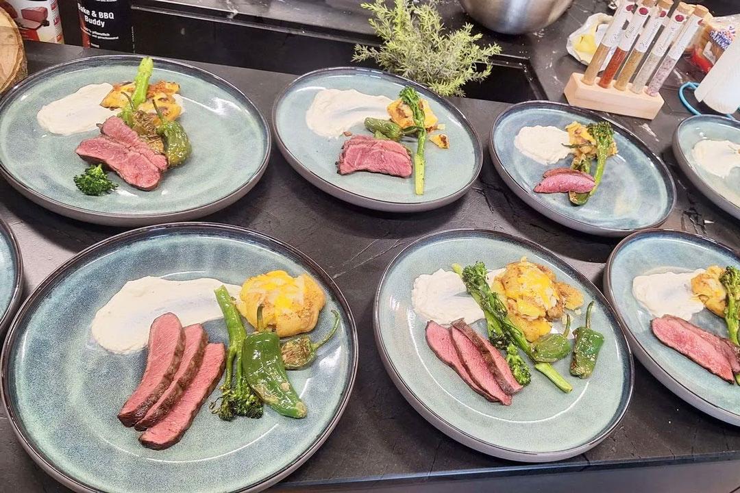 Perfekt angerichtete Steaks mit Gemüse auf türkisfarbenen Tellern beim Afterwork Steak Grillkurs.