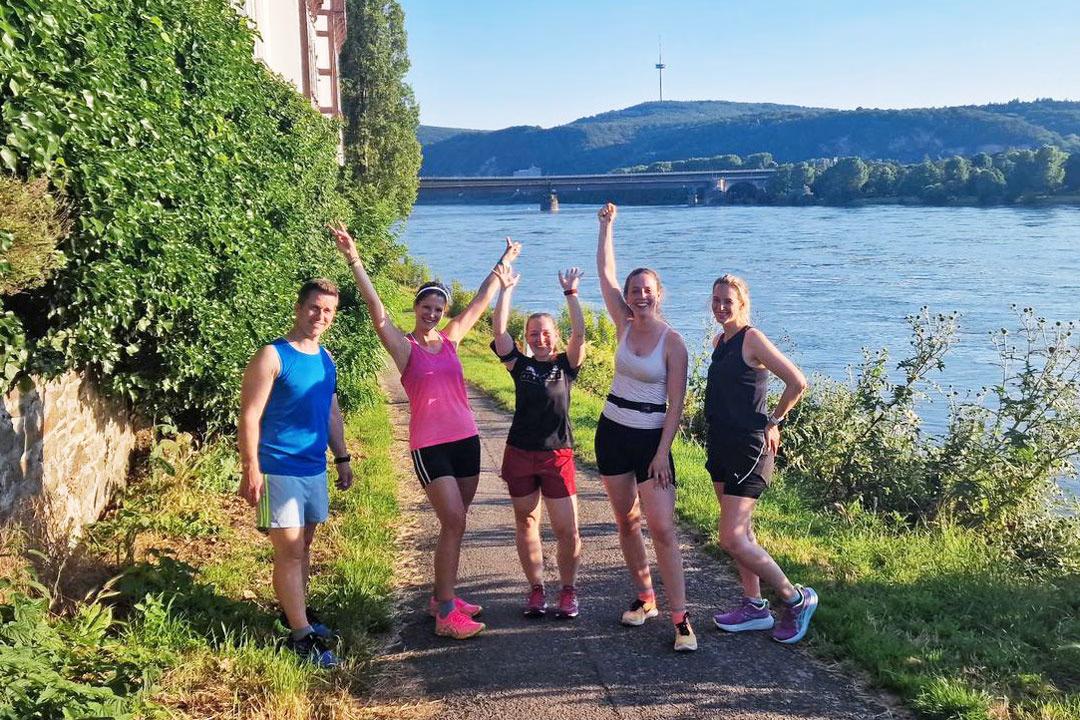 Running City Tour am Fluss: Jogging-Stadtführung mit sportlicher Gruppe und Ausblick auf die Natur.