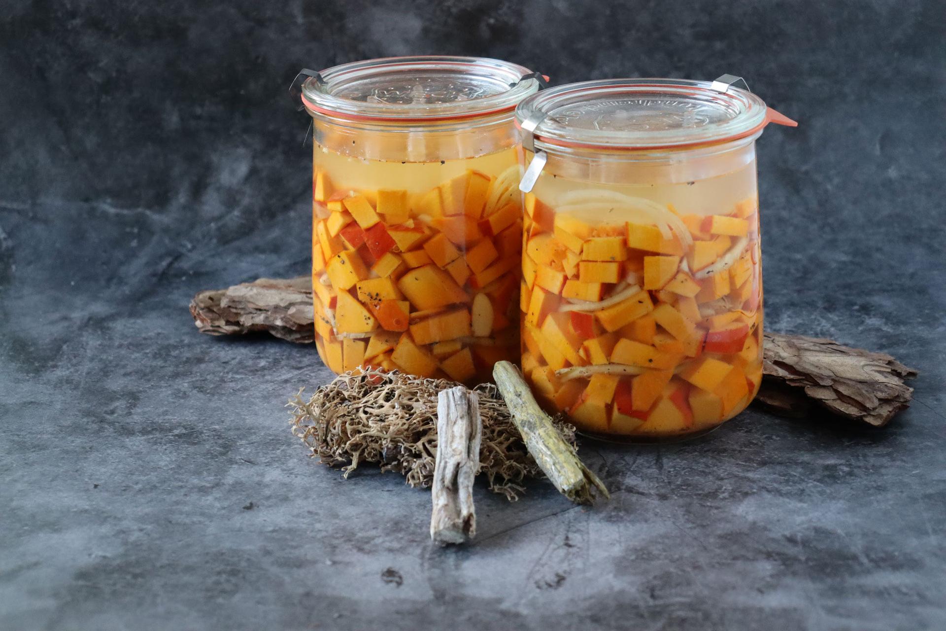 Zwei Einmachgläser mit fermentierten Lebensmitteln vor schwarzem Hintergrund im Kochkurs "Grundlagen der Fermentation".