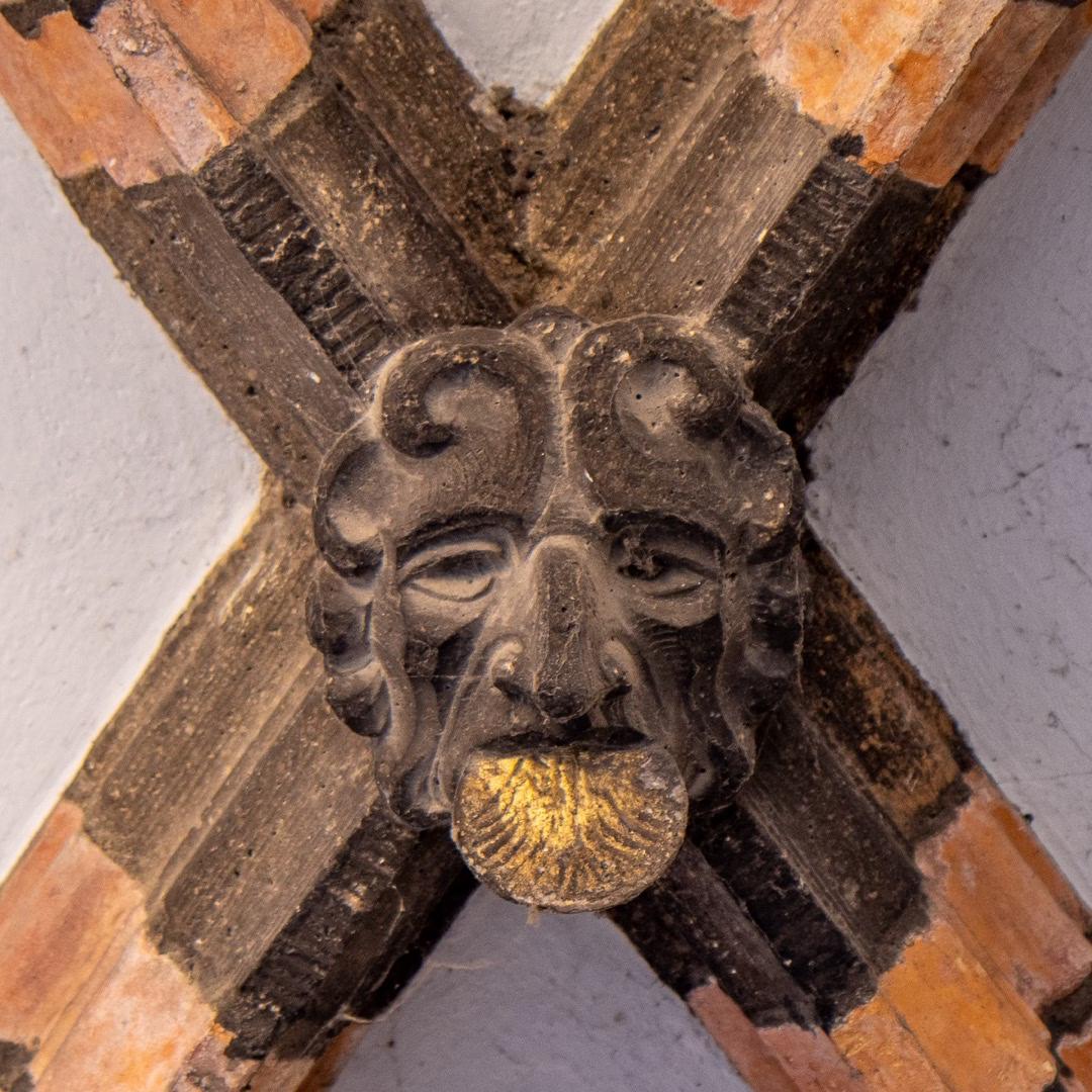 Steinmaske mit goldener Münze im Mund, Teil einer Gewölbedekoration in St. Marien in Lübeck.