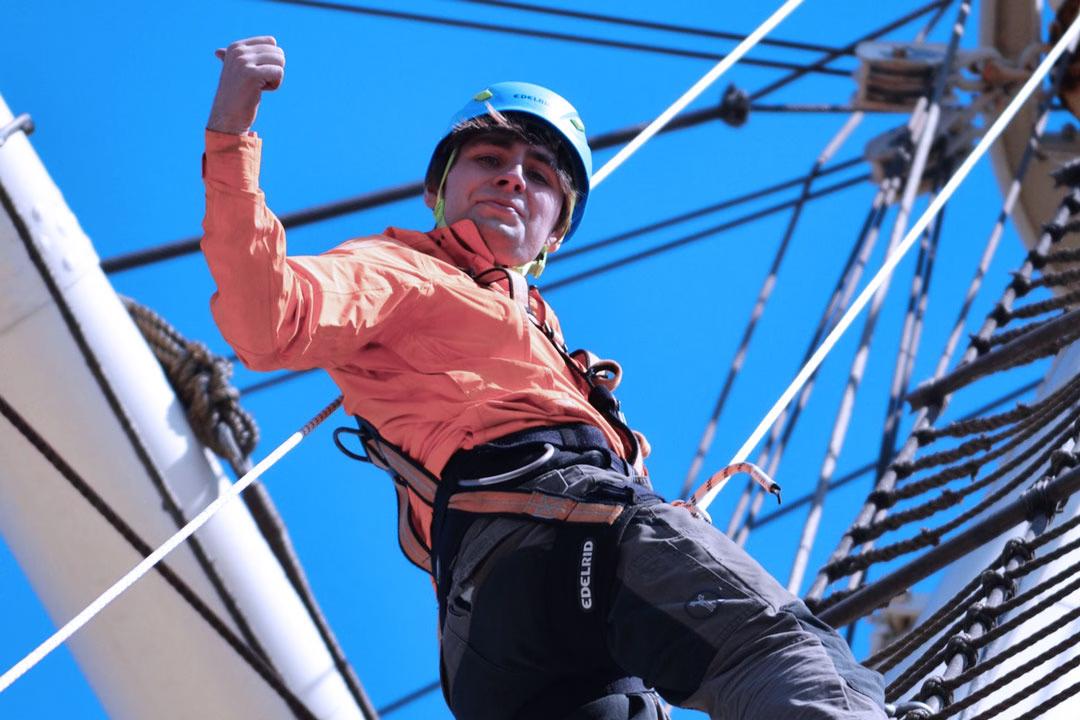 Nahaufnahme eines Kletterers mit Helm und Gurt im Mast der Rickmer Rickmers.