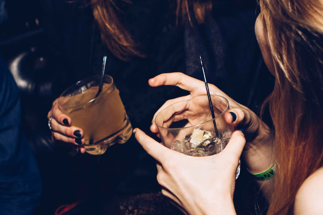 Zwei Frauen stoßen mit Drinks in einer Bar an.