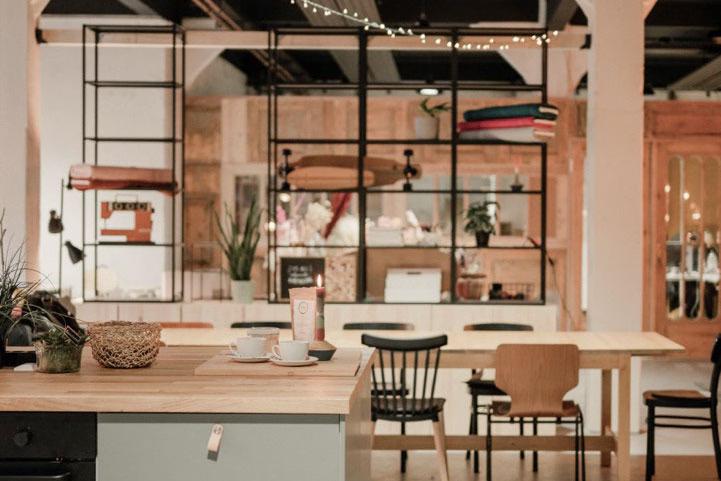 Einblick in die Machbar in Lübeck: ein kreativer Ort im industriellen Stil mit hohen Decken, langen Tisch und kleiner Theke.