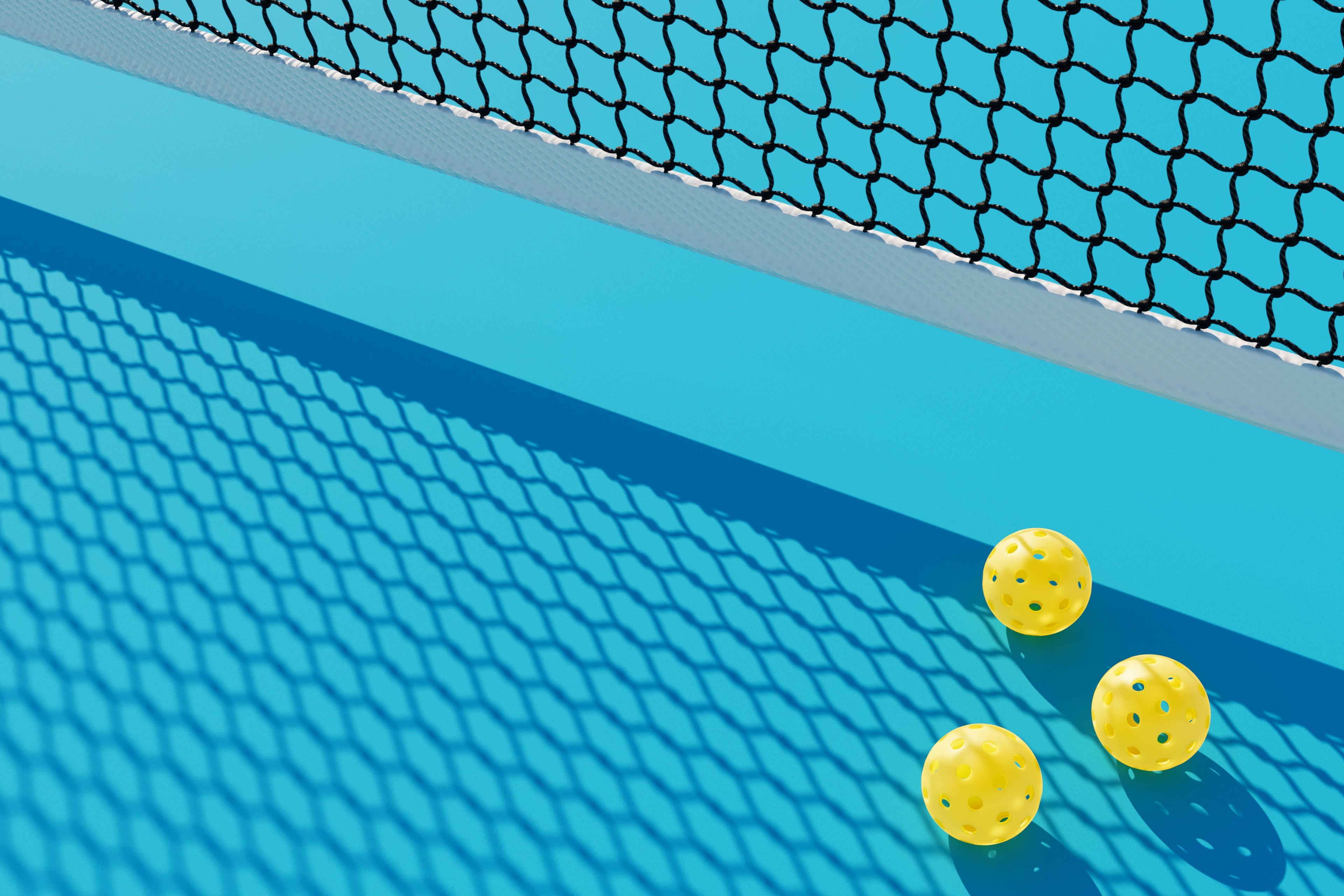 3 Pickleball-Bälle unter einem Netz