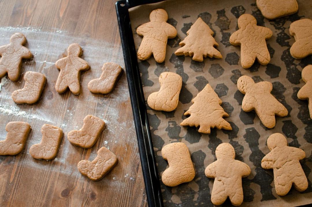 Lebkuchen-Plätzchen in Form von Stiefel, Tanne und Männchen liegen auf einem Backbleck.