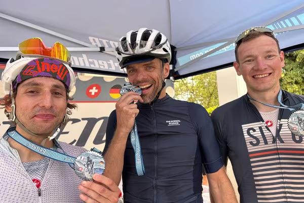 Finisher des Ultra-Distanz-Rennrad-Marathon, drei lächelnde Männer mit Medallien.