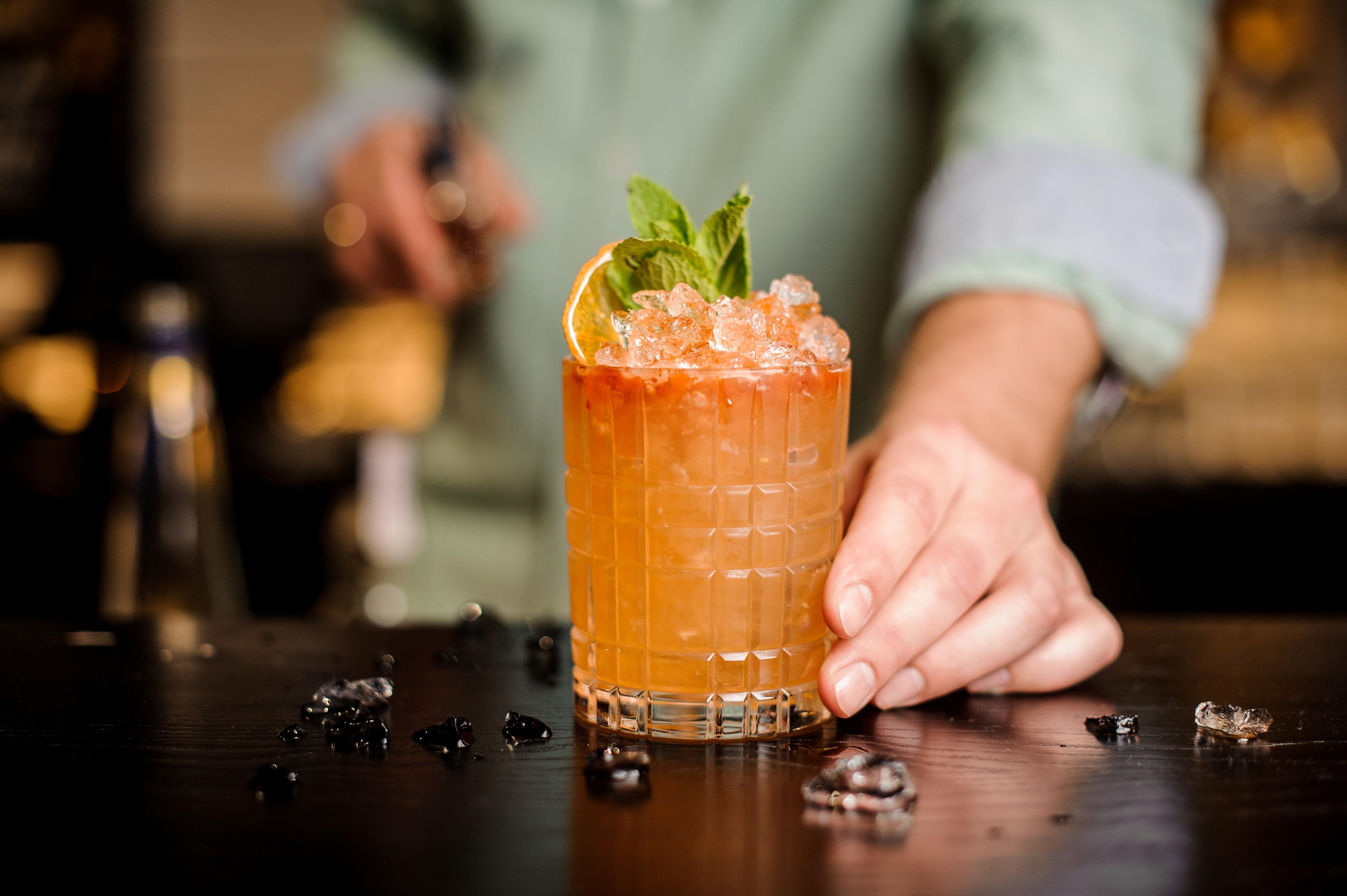 Ein Barkeeper präsentiert einen Cocktail mit Eis und Dekoration