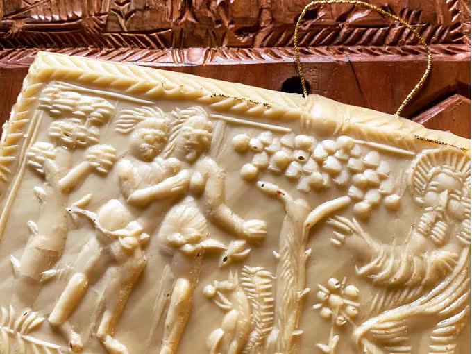 Alte Lebkuchenform aus Holz mit kunstvollen Verzierungen, die sich auf das Lebkuchengebäck davor abgedrückt haben.