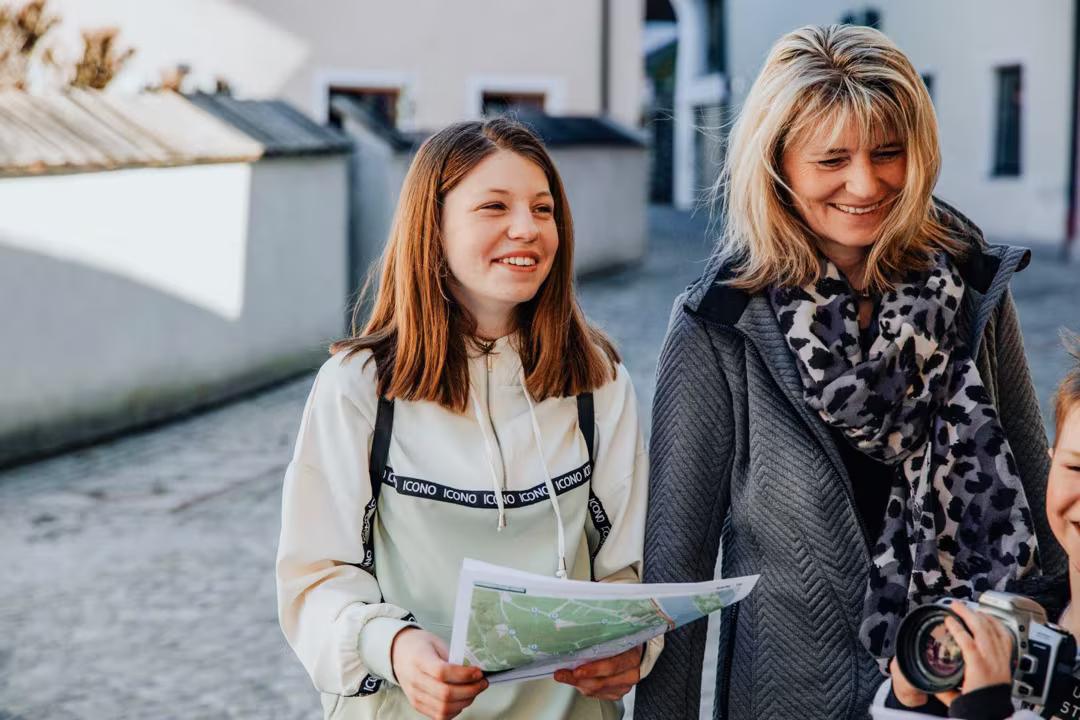 Mutter und Tochter lachen, die Tochter hält die Schatzkarte des Detektiv-Trail Grömitz in der Hand.