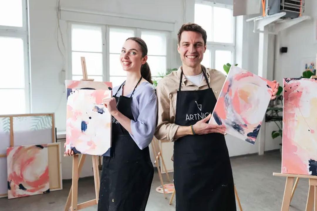 Eine Frau und ein Mann zeigen ihre Kunstwerke der ArtNight in einem hellen Atelier.