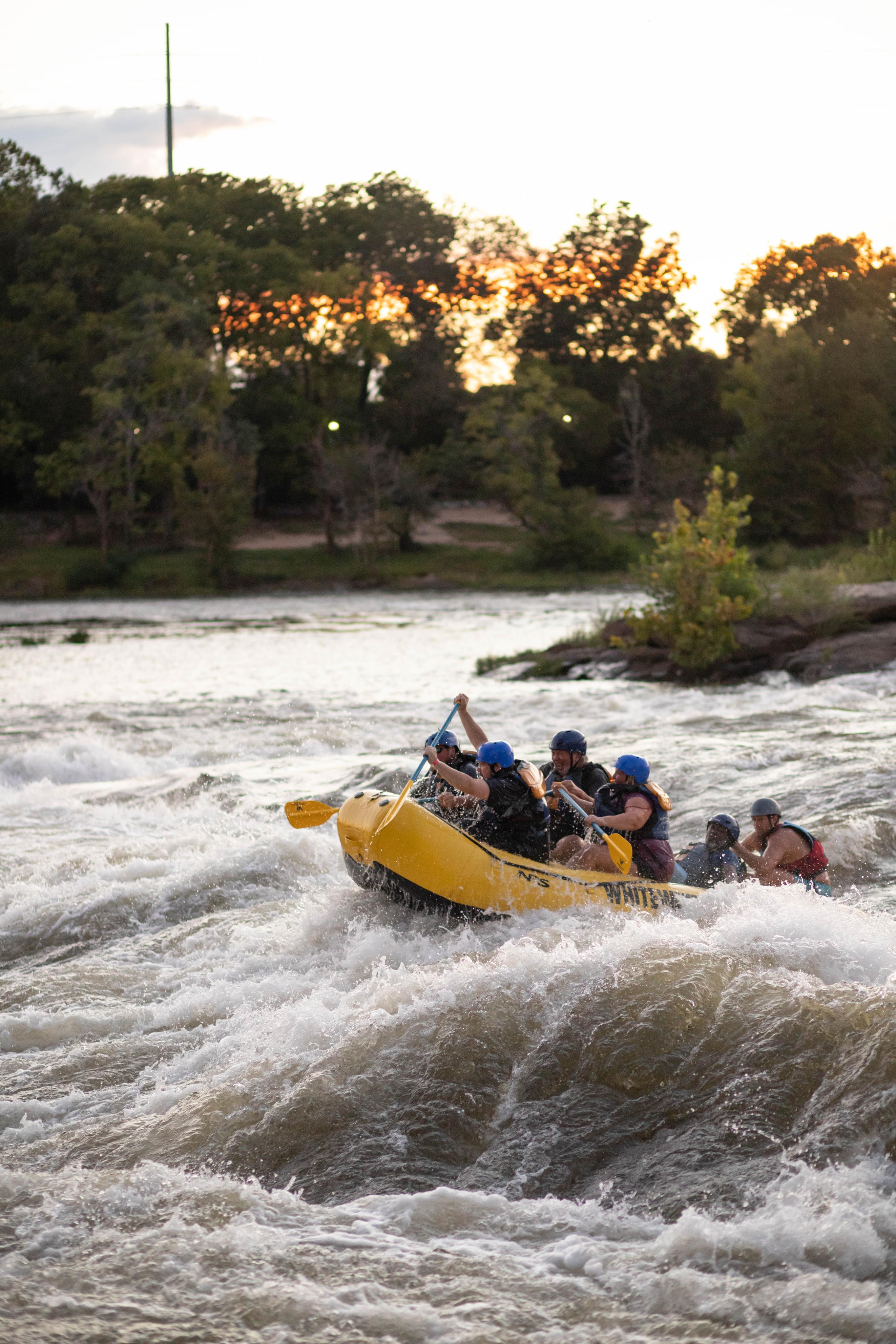 Ein Rafting Boot mit einer Gruppe Menschen auf einem turbulenten Gewässer.