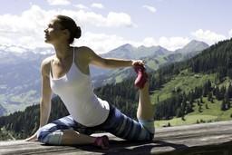 Eine Frau kniet bei einer Yoga-Übung vor den Alpen
