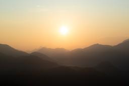 Sonnenaufgang bei diesigem Wetter über Berggipfeln