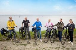 Eine Gruppe steht mit Fahrrädern an der Ostsee