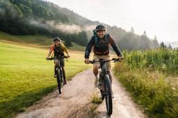Zwei Menschen fahren mit E-Mountainbikes durch die bayerische Berglandschaft