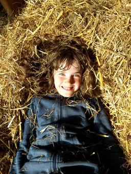 Ein Kind liegt im Stroh und lacht