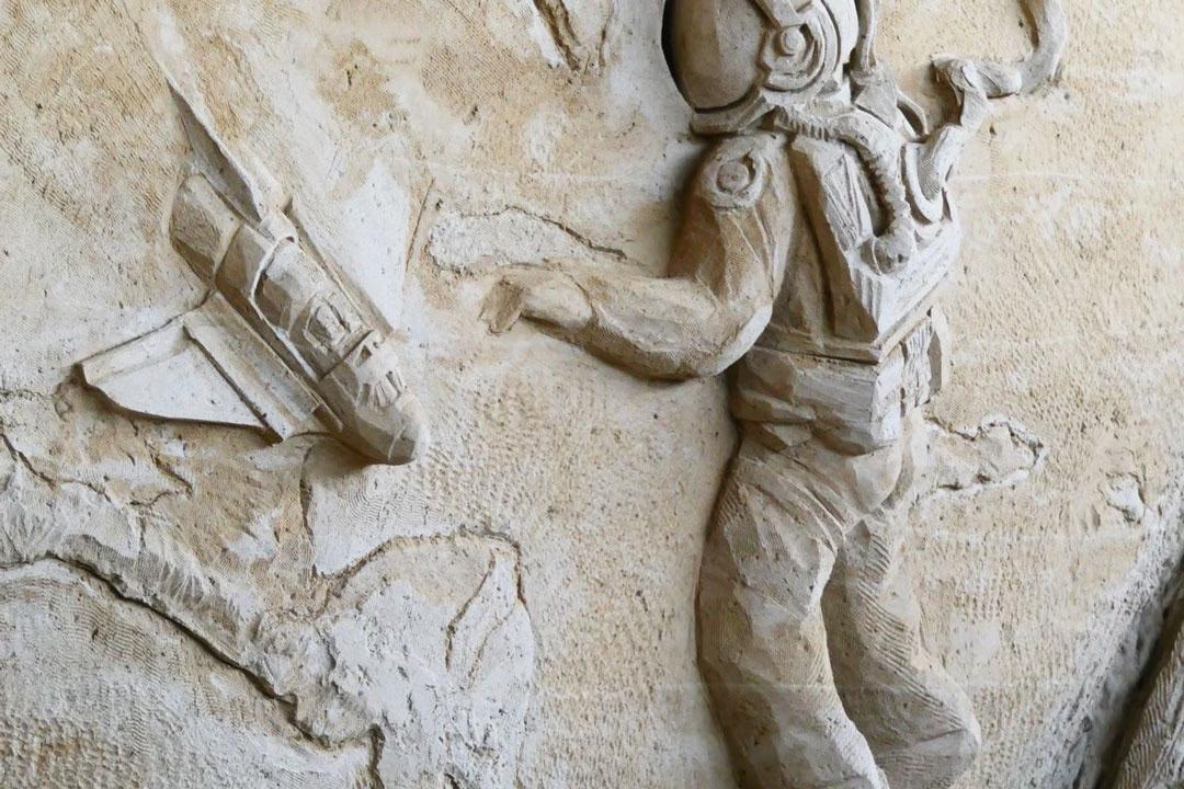 Detailreiches Sandrelief in der Sandskulpturenausstellung zeigt einen Astronauten im Raumanzug mit einer Rakete.