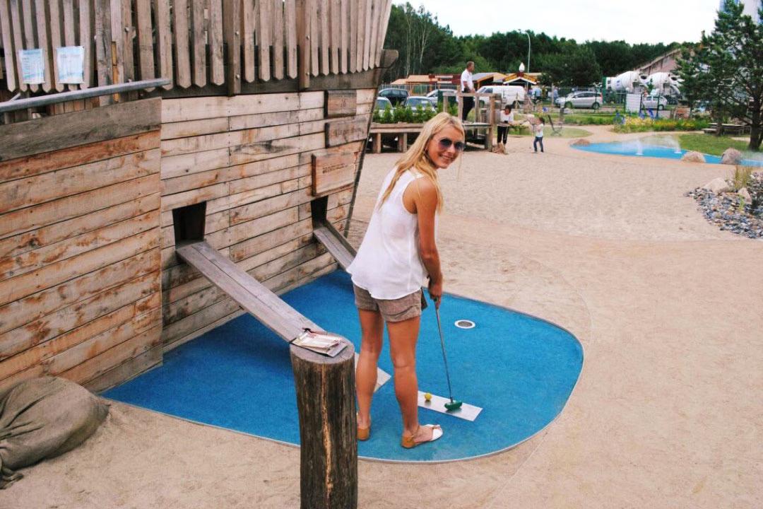 Eine Spielerin vor dem Piratenschiff mit Schläger in der Hand auf der Minigolf-Anlage Piraten der Ostsee.
