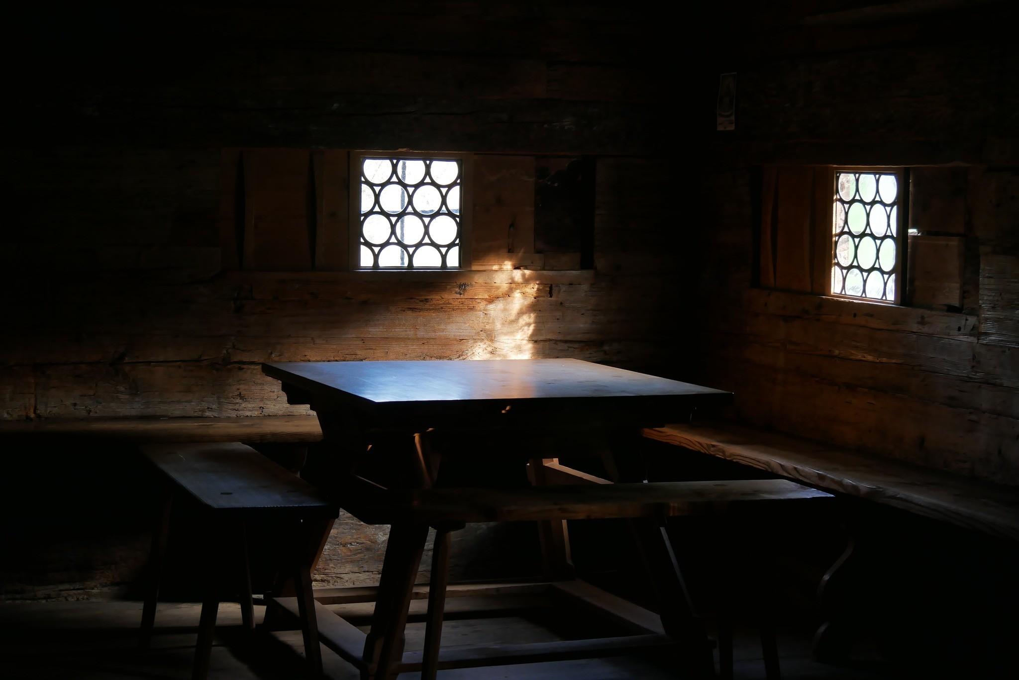 Licht fällt auf einen Tisch in einer dunklen Bauernstube