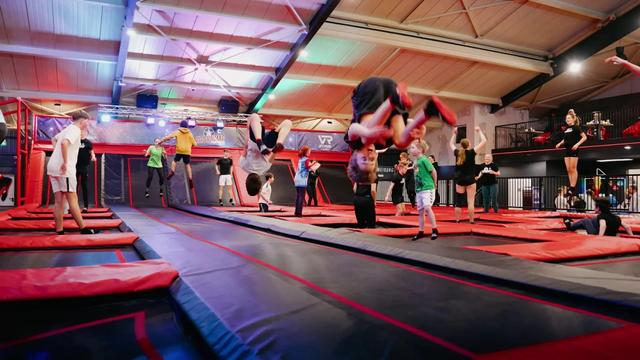 Kinder springen auf rot-schwarzen Trampolinen in der Trampolinhalle EasyJump in Grömitz