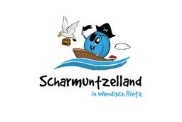 Logo des Scharmuntzellands mit dem blauen, runden Maskottchen Scharmuntzel in einem Boot