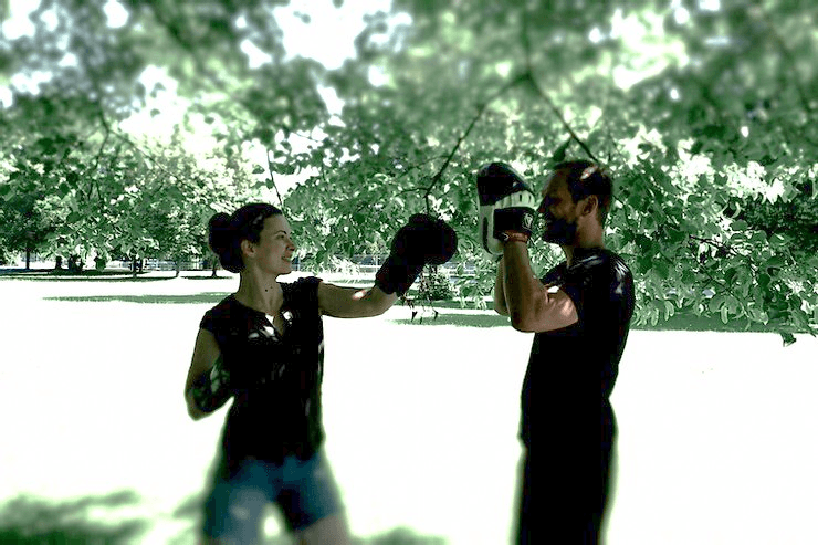 Eine Frau boxt in einem Park bei einem Coaching mit Christoph Öller