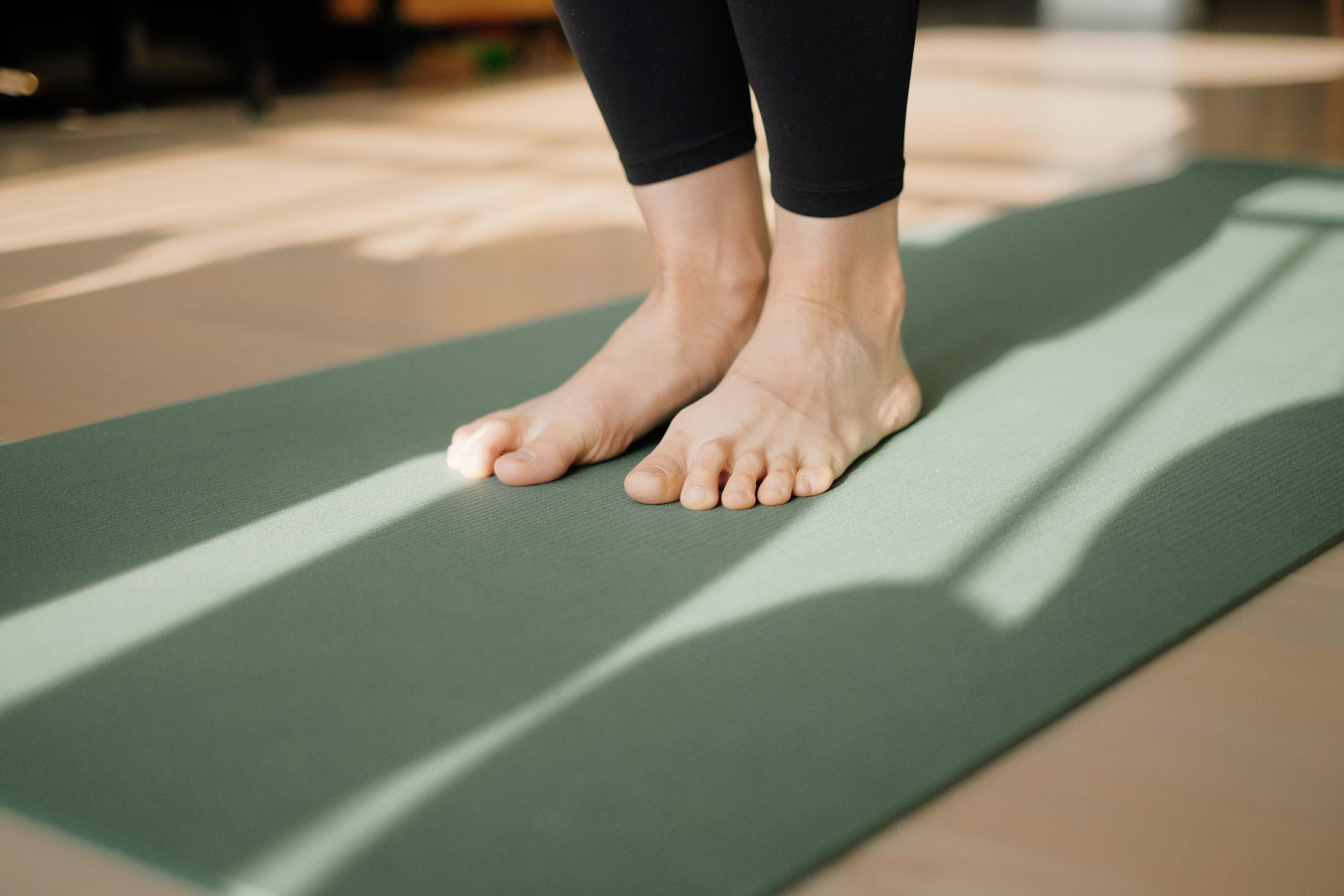 Zwei nackte Füße auf einer grünen Yoga-Matte