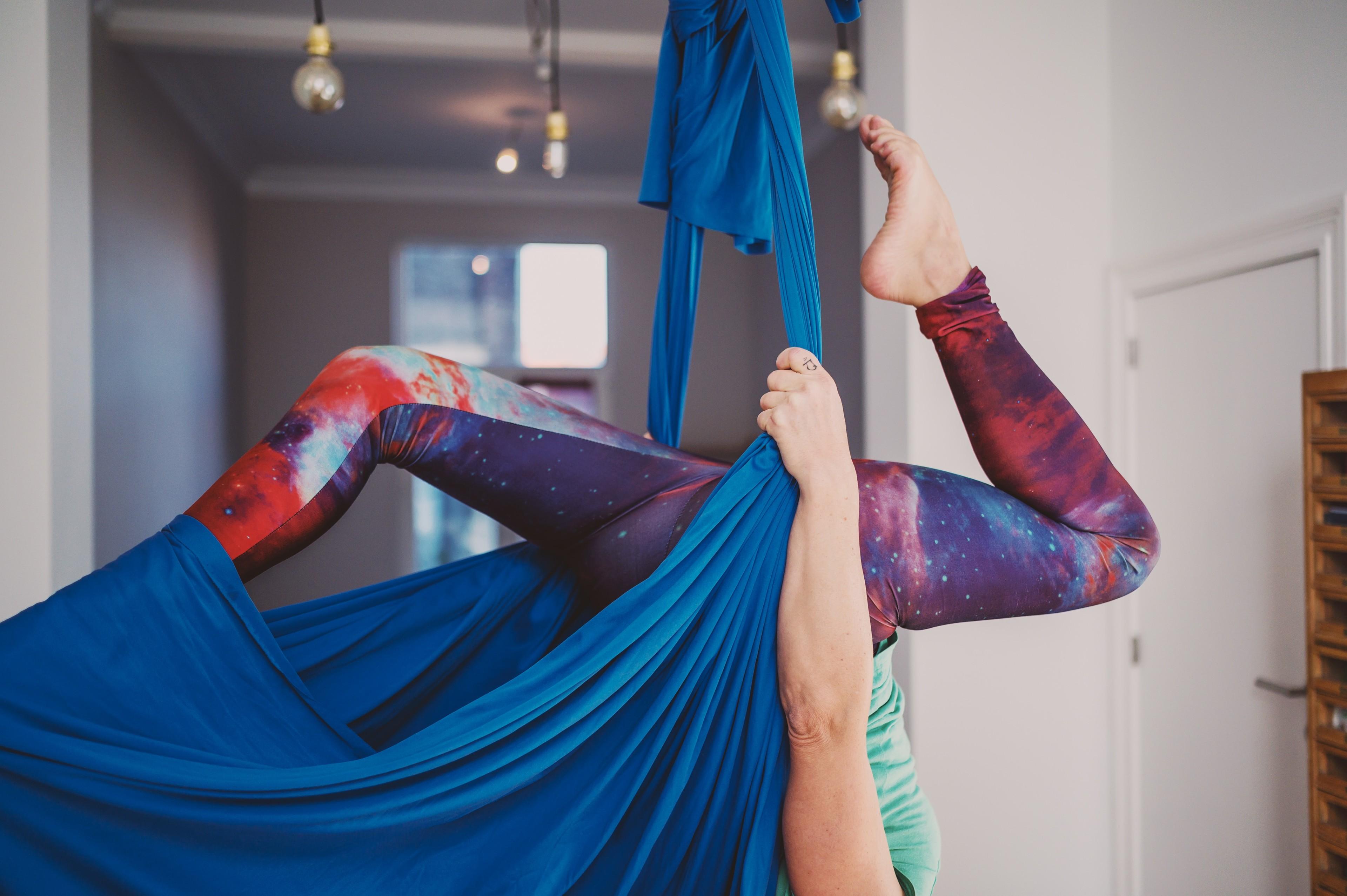 Eine Frau hängt kopfüber in einem blauen Aerial-Yoga-Tuch