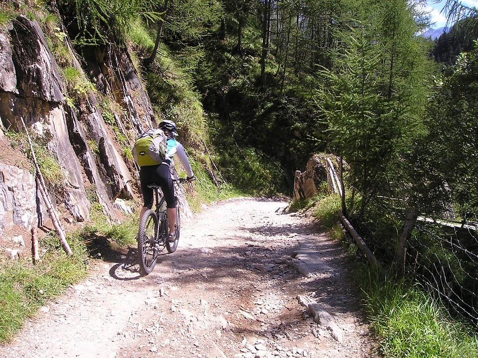 Ein Person fährt Mountainbike auf einem unbefestigten Weg in den Bergen