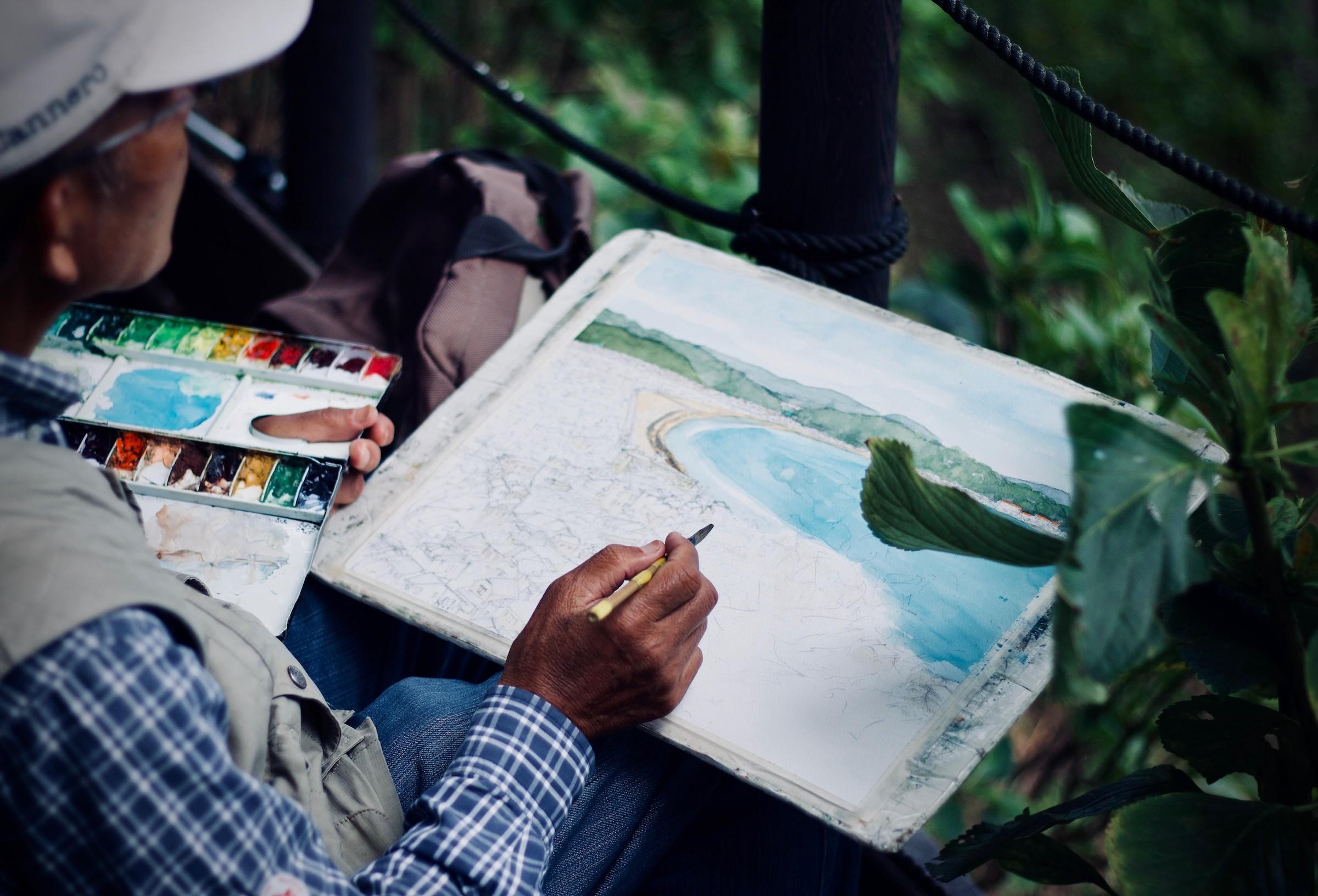Ein Mann fertigt eine Aquarell-Skizze von einer Bucht an