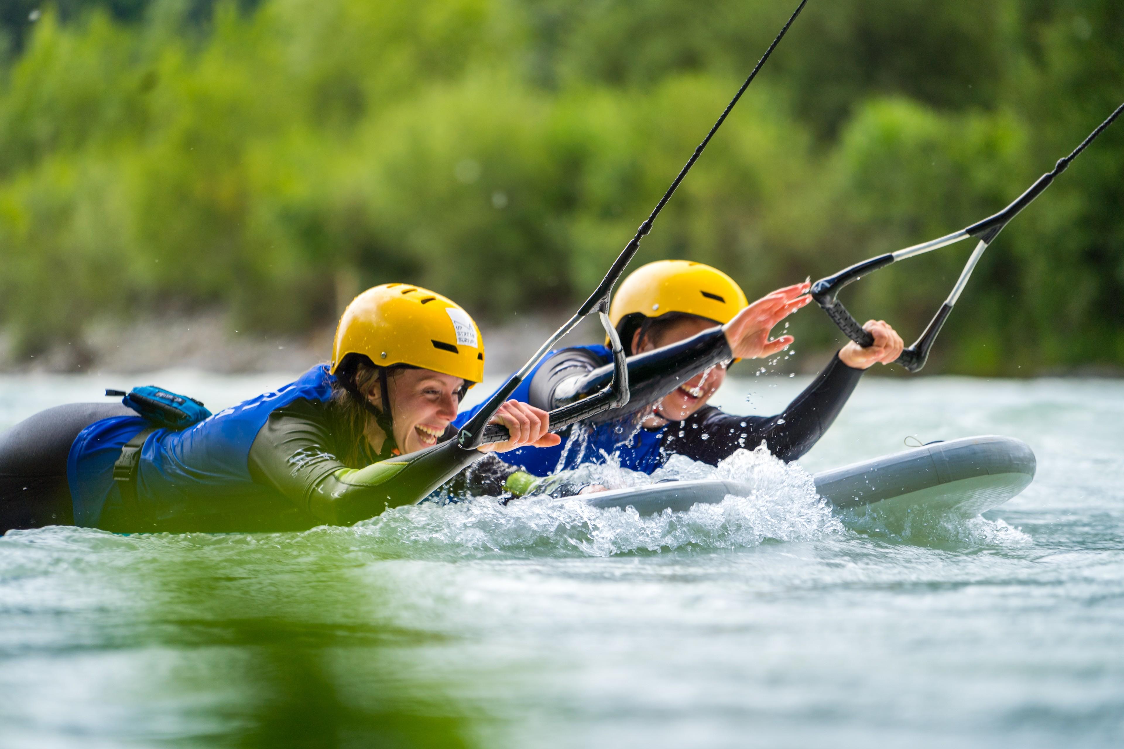 Zwei Menschen liegen beim Upstream-Surfing bäuchlings auf Surfbrettern