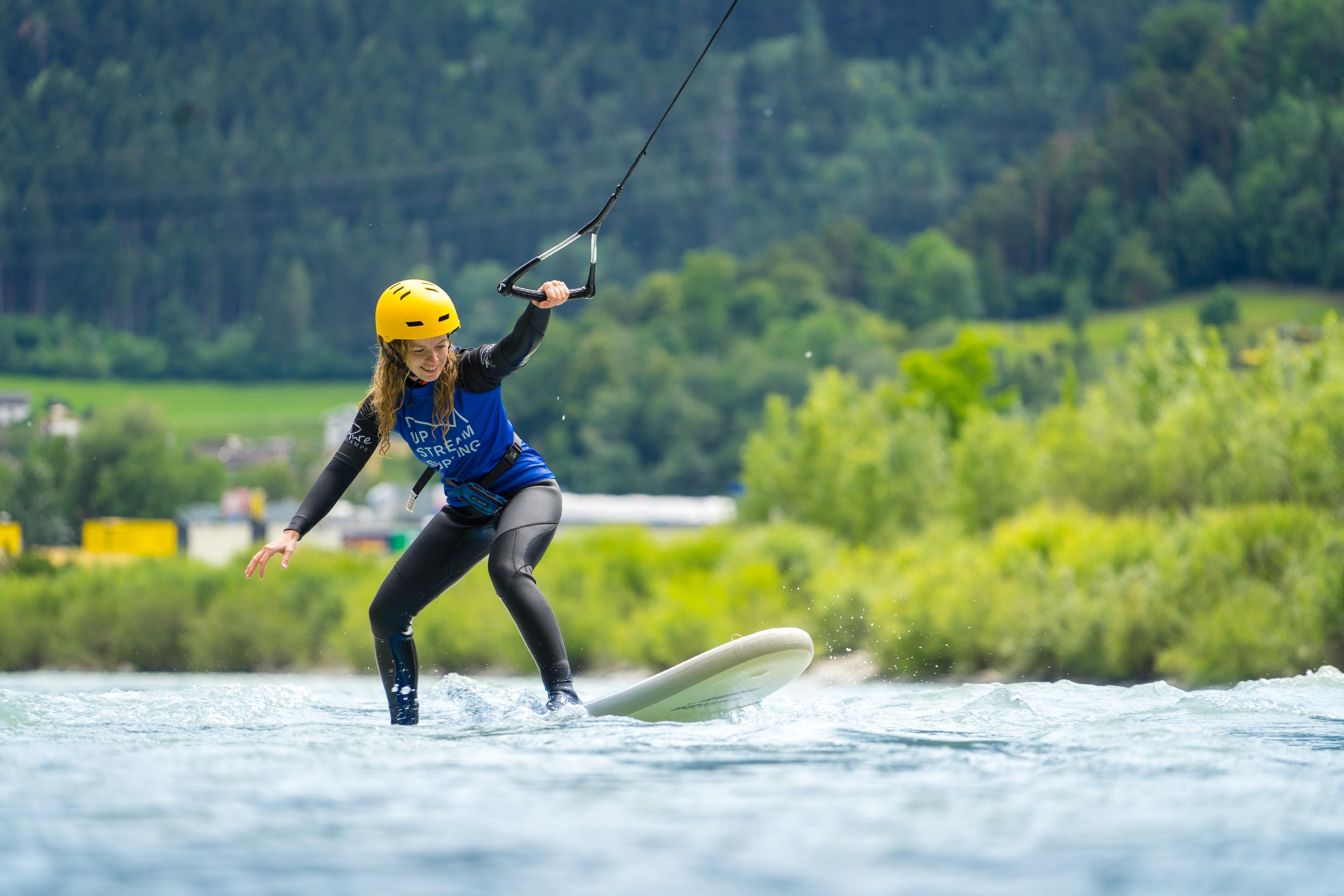 Eine Frau balanciert beim Upstream-Surfing auf einem Surfbrett