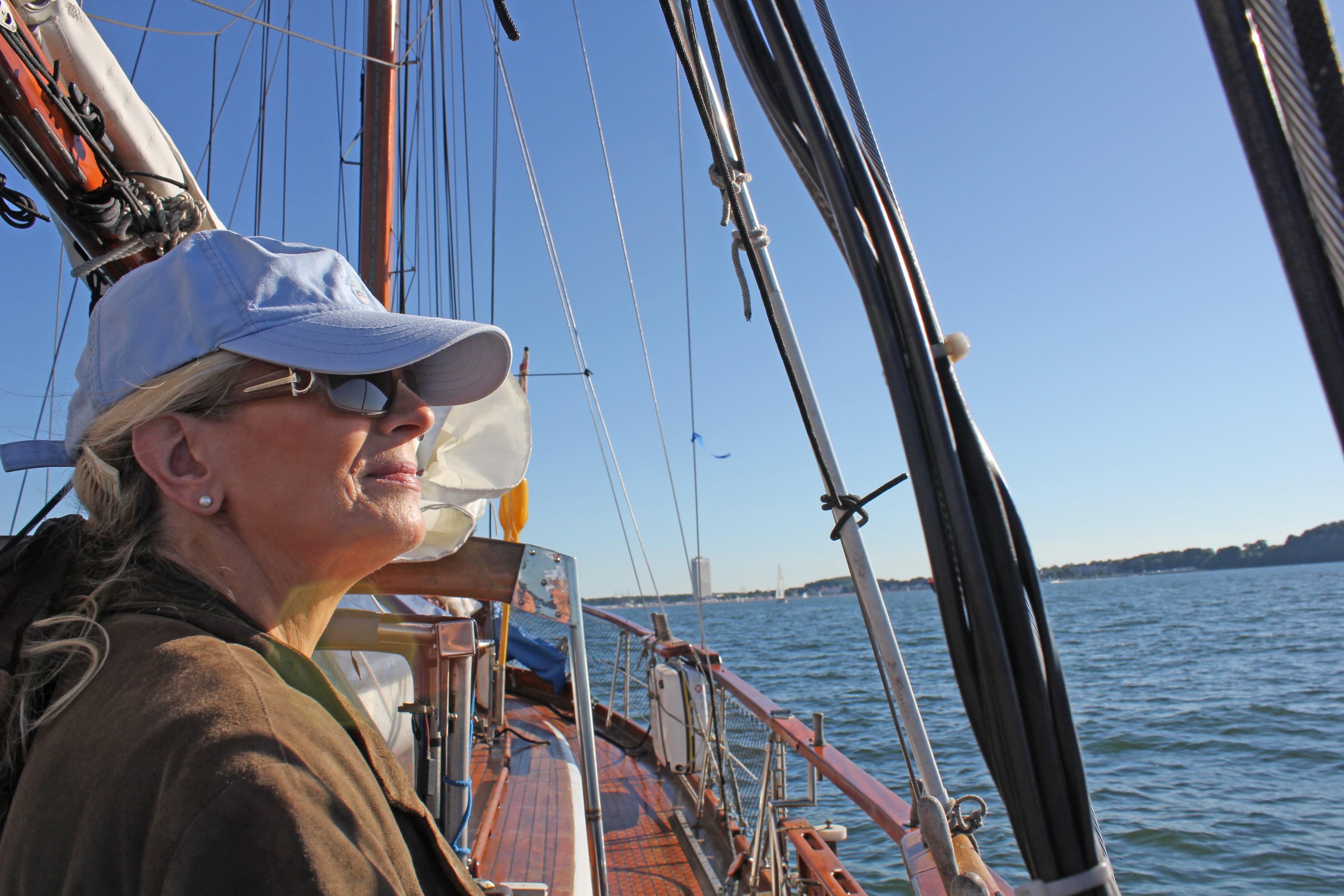Eine Frau auf einem Segelschiff blickt aufs Meer